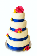 Elegant three-tiered wedding cake with blue ribbons, pink roses, and yellow flowers, decorated textured surface.